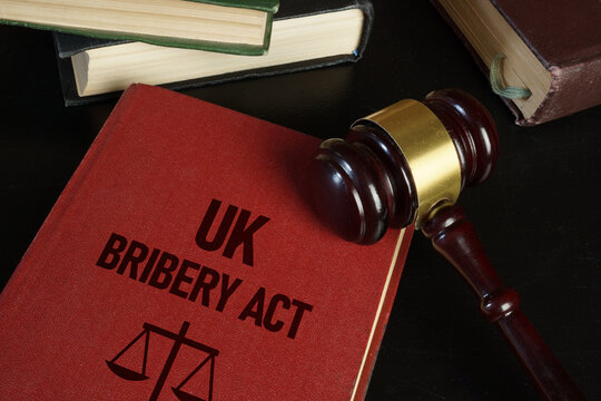 UK Bribery Act Legal Compliance Concept with Judge Gavel Law Books and Anti Corruption Legislation Reference on Dark Background