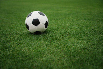 Fototapeta premium A soccer ball rests on a lush green field, symbolizing football competition, teamwork, athletic performance, sportsmanship, and the simplicity of the beautiful game.