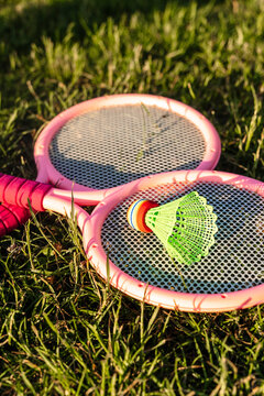 Pink badminton rackets and a shuttlecock on green grass.