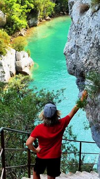 back view of a hiker looking down at the turquoise water of the gorges du verdon canyon in france