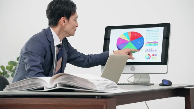 オフィスでPCを見ながら仕事する男性ビジネスパーソン
