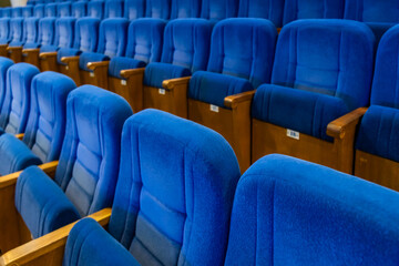 Fototapeta premium Rows of empty blue seats in a cinema hall. Comfortable velvet chairs for viewers inside an auditorium. Interior of a theate