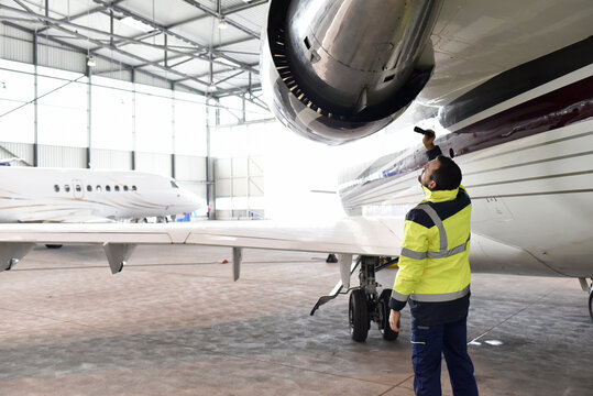 Aircraft mechanic inspects and checks the technology of a jet in a hangar at the airport