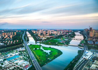 Obraz premium Aerial view of the Grand Canal in Tongzhou District, Beijing, at dawn, showcasing the modern urban waterfront scenery and livable city landscape.