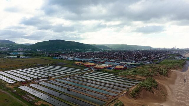 Pushing Aerial View of Commercial Ragworm Farm and Marine Bait Production. Sediment beds and water filtration systems used to cultivate ragworms for the global fishing bait market. United Kingdom. 4K.