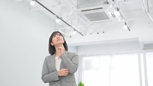オフィスの天井設備を確認する女性ビジネスパーソン