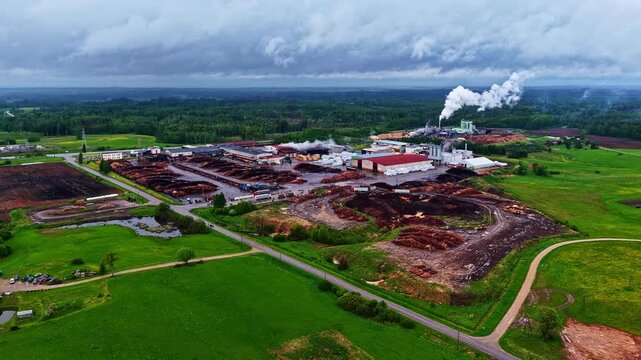 The Stora Enso sawmill complex is surrounded by lush greenery, with smoke rising from chimneys. Ideal for industrial and environmental content.