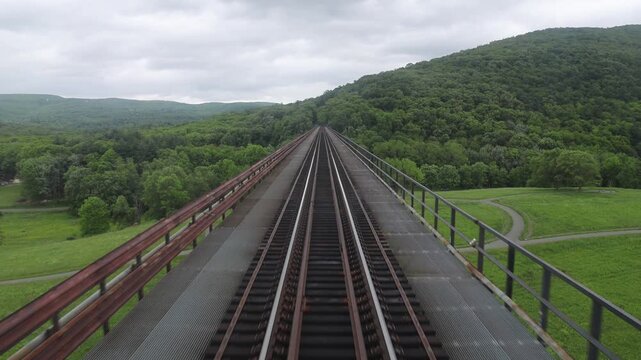 view from back of new jersey train from moodna viaduct of valley between mountains upstate new york (transit rail track railroad travel commute commuter line) port jervis new york