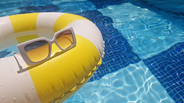 Summer vacation, summertime, tourism, travel concept.  A yellow and white striped inflatable ring with sunglasses floating in a bright turquoise blue swimming pool.  Space for text. 