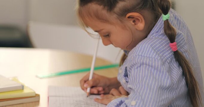 Close up of a cute little girl focusing on writing in her notebook.