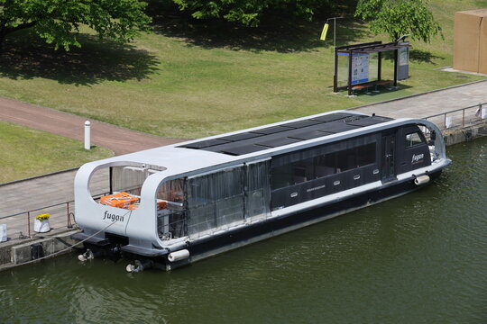 A modern solar powered cruise boat docks along a canal.
