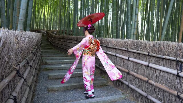 Asian woman wearing a traditional Japanese kimono at Bamboo Forest in Kyoto, Japan