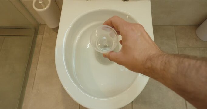 showing hands opening a urine sample container above a toilet for medical testing and laboratory analysis. Suitable for healthcare, diagnostics, urine tests, medical procedures, and clinical concepts.