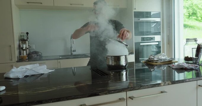 man reacting to smoke and using a towel to smother a kitchen fire on the stove. Suitable for kitchen safety, fire emergency, accident prevention, home danger, cooking hazards, and household safety