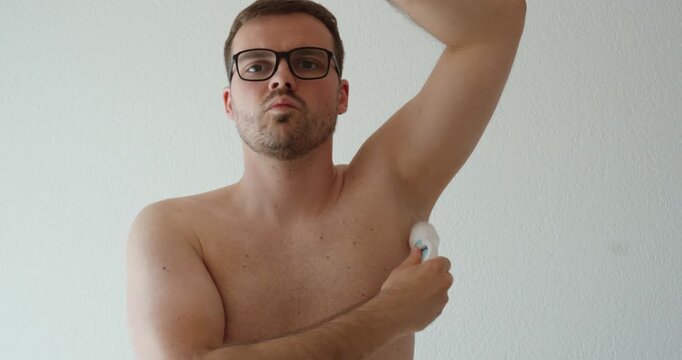 shirtless man applying roll-on deodorant to the underarm area. Suitable for personal hygiene, grooming, body care, freshness, skincare, men&rsquo;s wellness, and daily self-care routines.