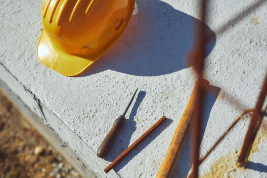 Construction tools and helmet on a cement foundation with iron rebar.