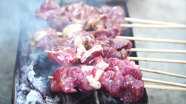 Close-up of Raw Mutton Satay Grilling on Charcoal Grill with Smoke