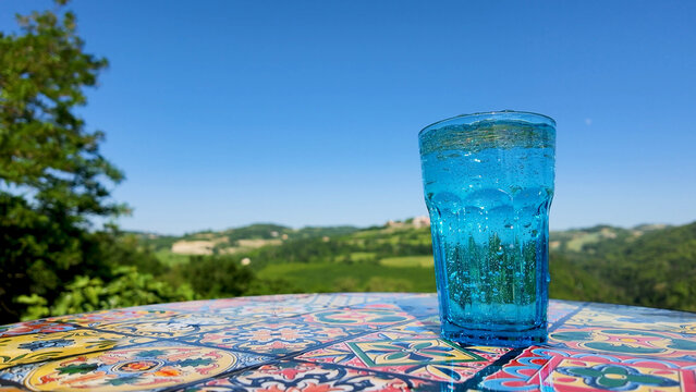 Sparkling Mineral Water in Blue Glass on Patterned Table with Scenic Hills
