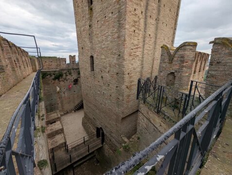 Imponente castello in pietra con torri merlate e mura storiche sotto un cielo grigio, per un&rsquo;atmosfera medievale forte e suggestiva