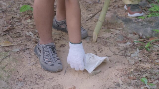 Close-Up Slow Motion of Boy&rsquo;s Hands Collecting Litter on Forest Trail