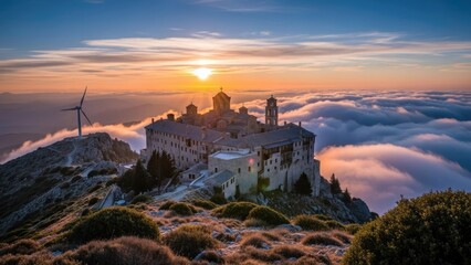 Obraz premium Ancient monastery on mountain peak above sea of clouds.