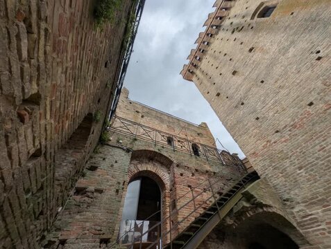 Imponente castello in pietra con torri merlate e mura storiche sotto un cielo grigio, per un&rsquo;atmosfera medievale forte e suggestiva