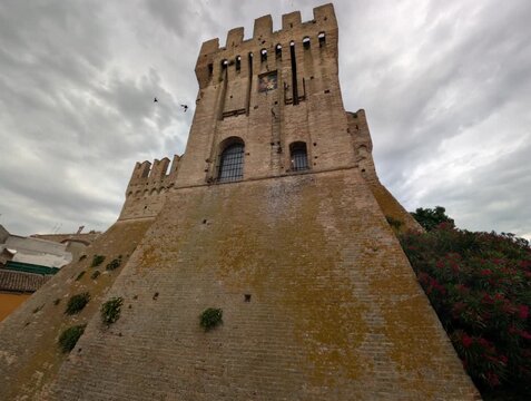 Imponente castello in pietra con torri merlate e mura storiche sotto un cielo grigio, per un&rsquo;atmosfera medievale forte e suggestiva