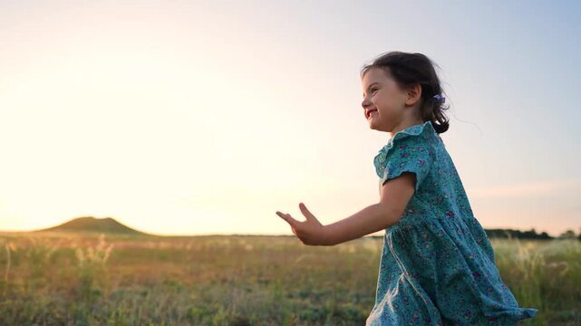A girl runs joyfully through a grassy field, with the sun setting in the background. The girl seems playful as she enjoys the outdoor scenery filled with tall grass.