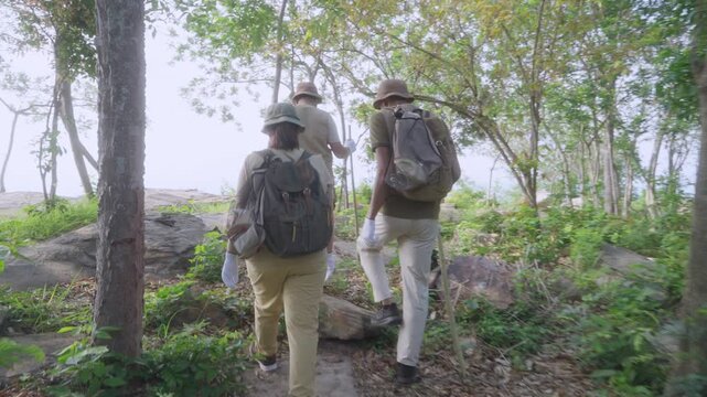Rear View of Asian Family Walking on Forest Trail During Cleanup Activity