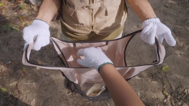 Top Down View of Child Placing Litter into Reusable Collection Bag