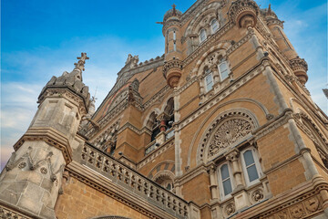 Fototapeta premium Mumbai Maharashtra India Jan 18 2026 Low angle architectural view of the ornate stone facade and soaring towers of Chhatrapati Shivaji Maharaj Terminus against a clear blue sky.