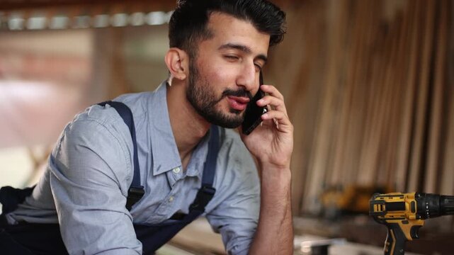 A man is sitting at a table with a cell phone in his hand