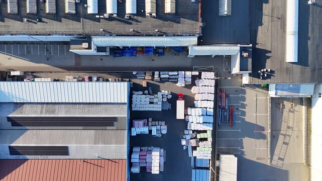 Aerial view of industrial zone showcasing warehouse roofs, stacked materials, and organized storage areas, highlighting the layout and structure of the facility in a commercial setting