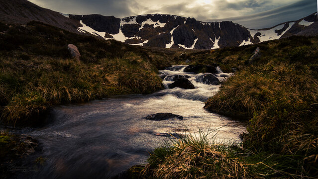 Mountain Stream Cascading Through Moorland with Snowy Corrie Backdrop, Cairngorms Scotland