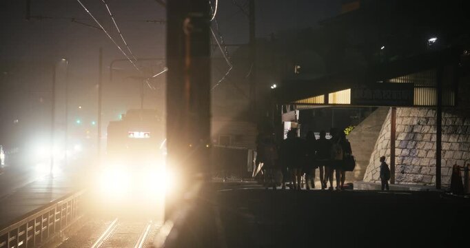 Group of People Silhouetted on Station Platform With Approaching Train In Night Fog