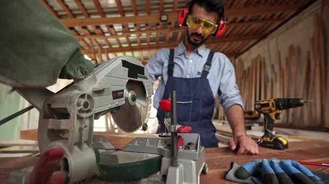 A man in a blue apron is working with a saw