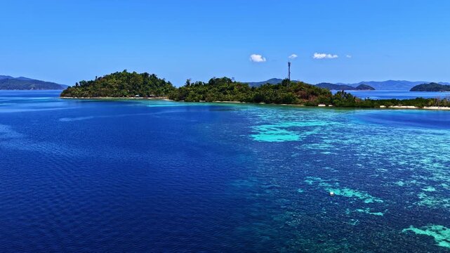 Breathtaking wide drone shot over Port Barton, Palawan, Philippines. Features a chain of lush green tropical islands surrounded by spectacular turquoise coral reefs and deep blue ocean waters.