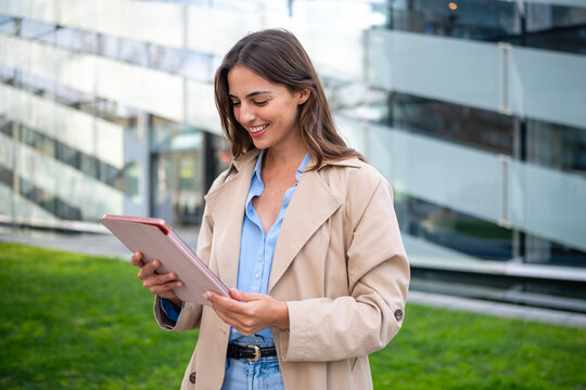Businesswoman smiling using digital tablet in front of modern building