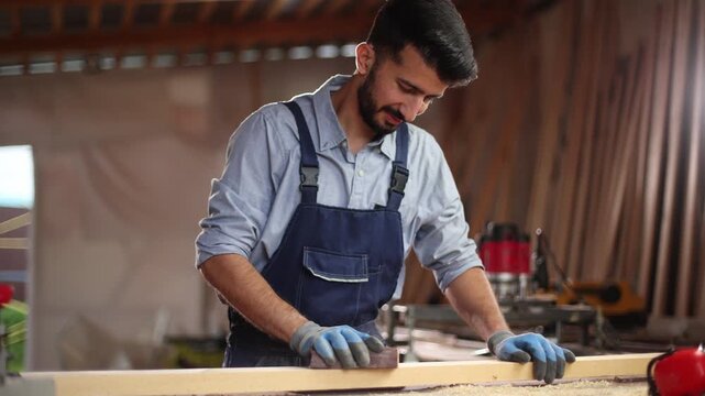 A man is sanding a piece of wood with a sanding block