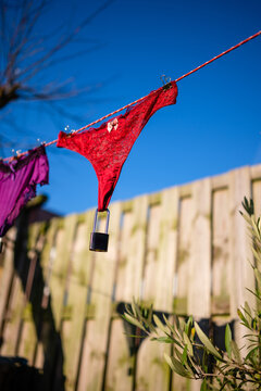 Red lace thong underwear hanging on a clothesline with a padlock, conceptual image of chastity and protection