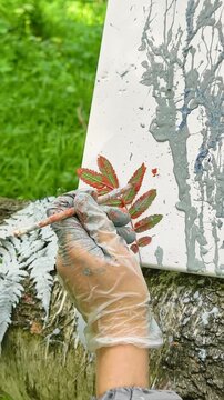 A gloved hand paints a fern branch with a brush. Highlights the delicate balance between control and spontaneity in Natural Brush Painting