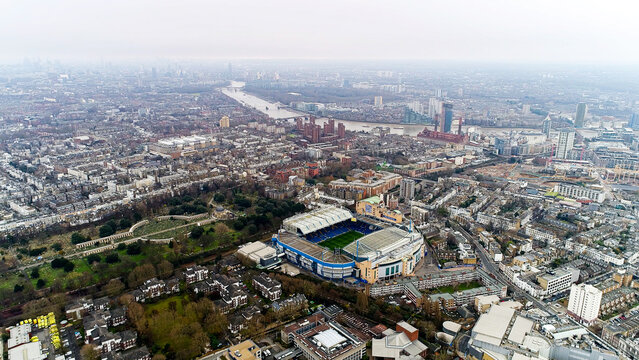 Aerial drone view of Stamford Bridge, Chelsea FC stadium, Brompton Cemetery, River Thames and London cityscape visible, Fulham, London, England, overcast