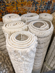 Naklejka premium Fluffy home carpets in light tones rolled into large rolls displayed in a supermarket offering soft and cozy flooring for interiors