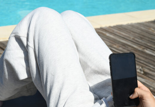 Pretty young girl on her sun lounger with her smartphone at a resort