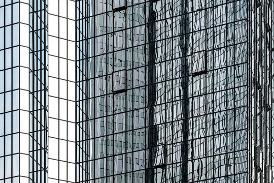Glass facade reflection stretches across grid lines and tower architecture, turning a business surface into abstract urban rhythm and depth