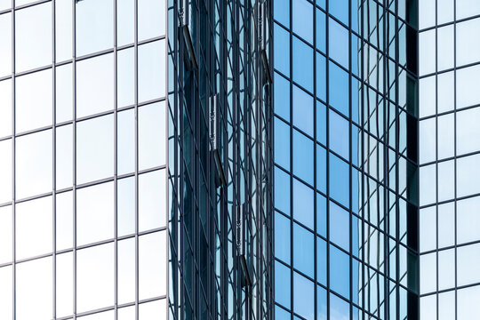 Blue glass facade grid catches tower reflection, architecture and windows, creating contrast across a business exterior in clear light