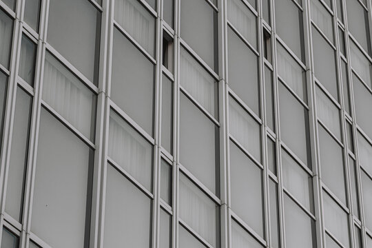 Metal facade grid and windows form architecture, building pattern, urban geometry and texture across a quiet abstract business exterior