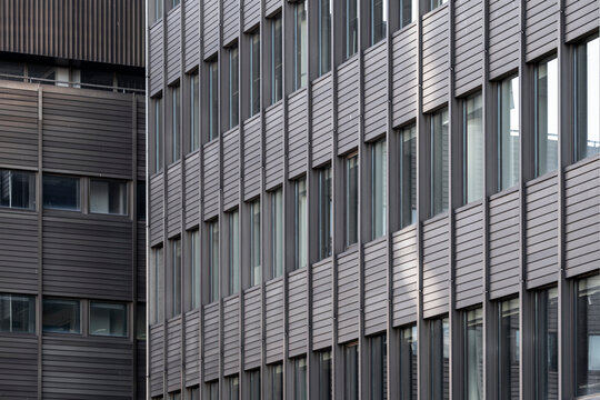 Gray facade windows repeat through architecture, building pattern, office grid and urban business texture across a compressed exterior wall