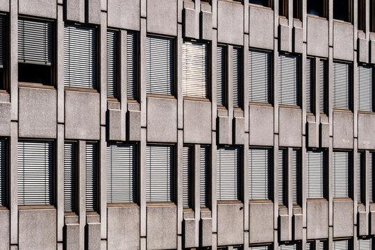 Concrete facade windows repeat across a grid pattern, giving architecture, building texture and urban business rhythm a precise exterior frame