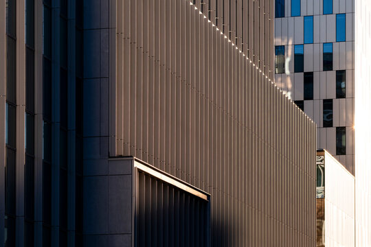 Metal facade shadows stretch through architecture, building lines, urban texture and business contrast along a dark exterior wall surface